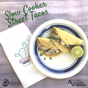 Two tacos from our Slow Cooker Street Tacos recipe topped with cilantro and lime juice, plated on a blue and white plate.