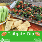 Tailgate dip recipe in a glass bowl with celery and tortilla chips.